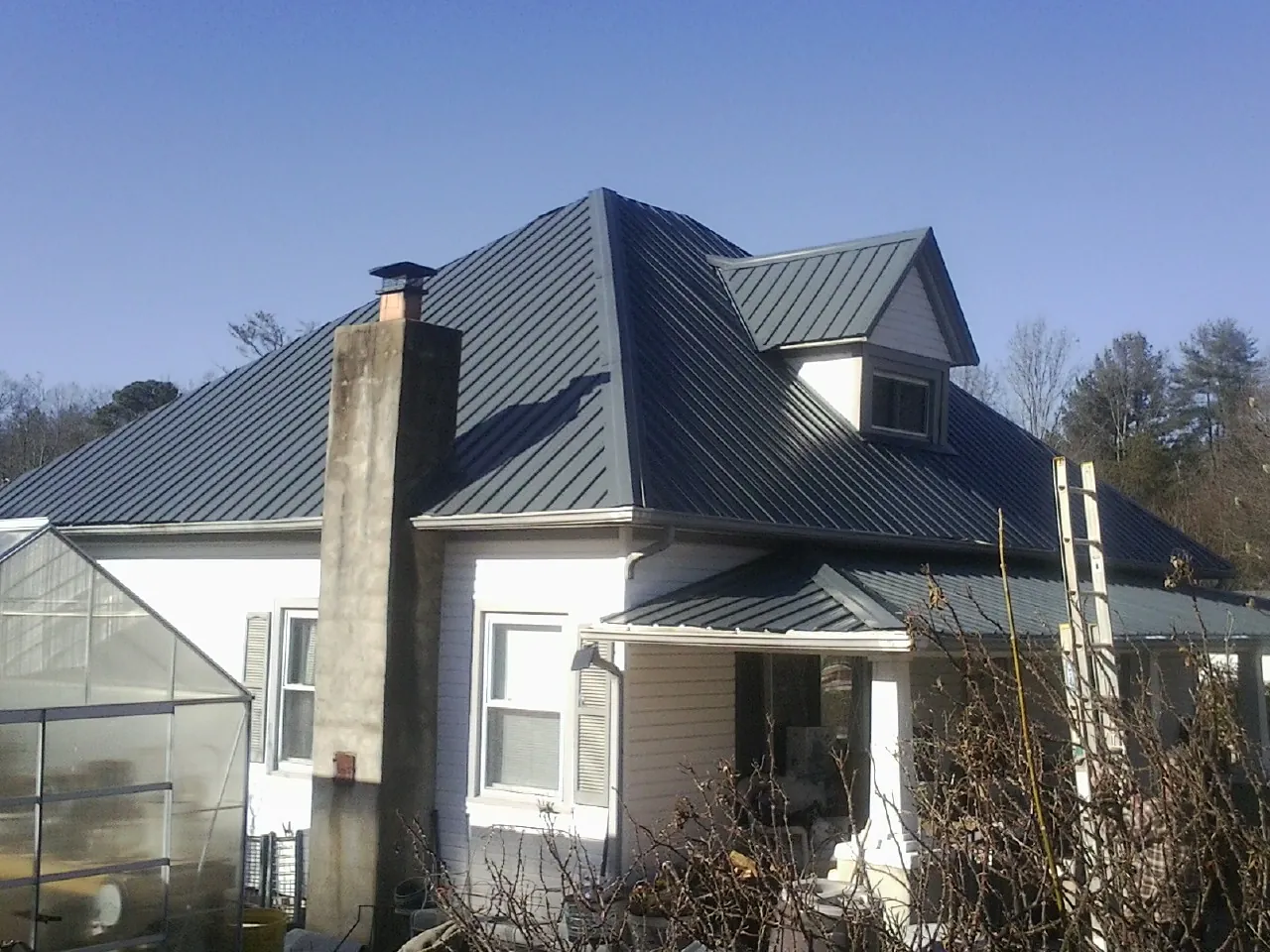 Dark blue standing seam metal roof on a white farmhouse with dormer — Slate & Tile Roof Repair by Roofing Brothers in Myrtle Creek