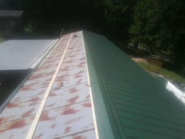 Old rusted panels beside newly installed green metal roofing — Wind Damage Roof Repair by Roofing Brothers in Myrtle Creek