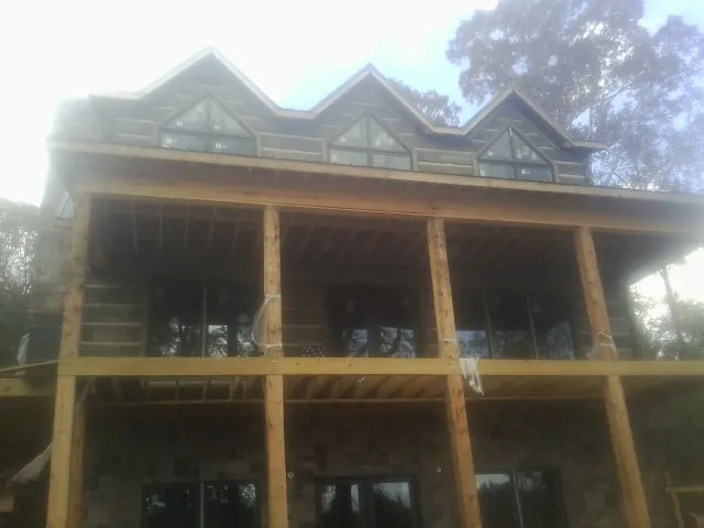 Dormers and porch framing on a large log home under construction — Roof Coating work by our crew in Myrtle Creek