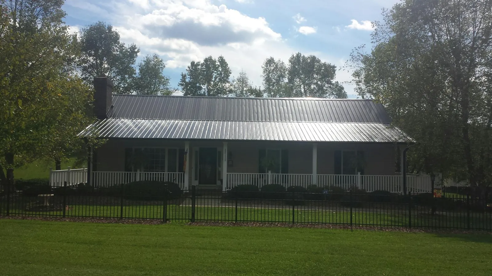 Gray metal roof on a brick ranch with a full width front porch — Gutter Guard Installation work by our crew in Myrtle Creek