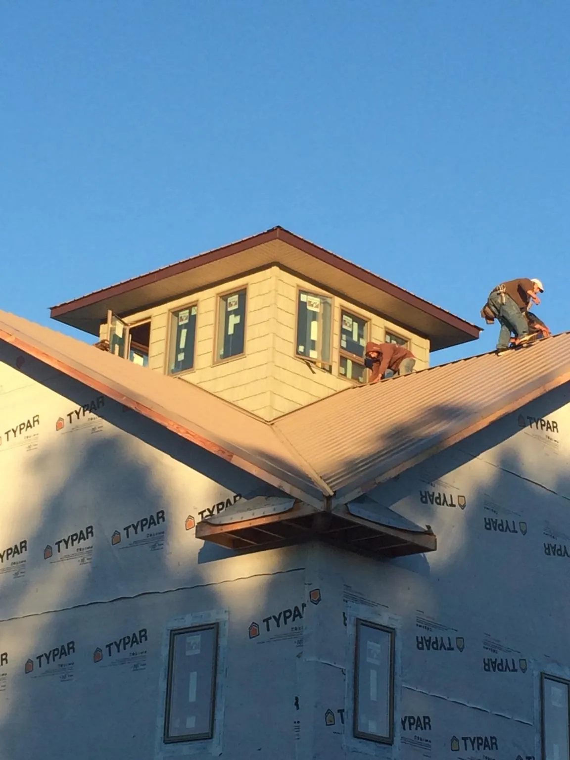 Roofers working around a rooftop cupola on a new metal roof at sunset — Roof Waterproofing in Myrtle Creek by Roofing Brothers